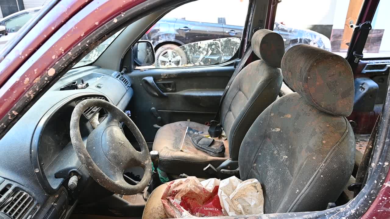 Interior view of an old car, showcasing dusty seats and steering wheel, caused by flood damage in Valencia
