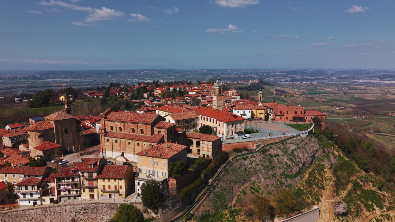 Historic bell tower and Piazza Castello in La Morra old town during a sunny day, aerial drone orbit
