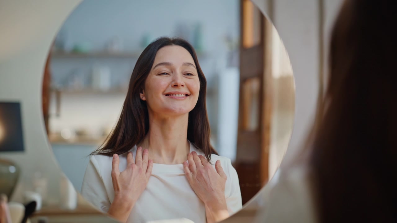 Morena realizando masaje facial mirándose al espejo en un ritual de belleza en casa, primer plano