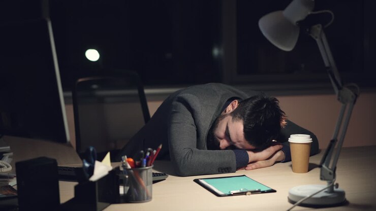 Uomo d'affari stanco che dorme alla scrivania di notte
