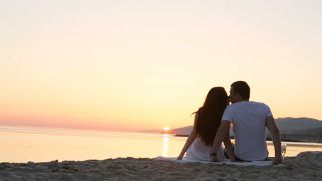 Couple looking at sunset. Back view of hugging couple looking at sunset on beach