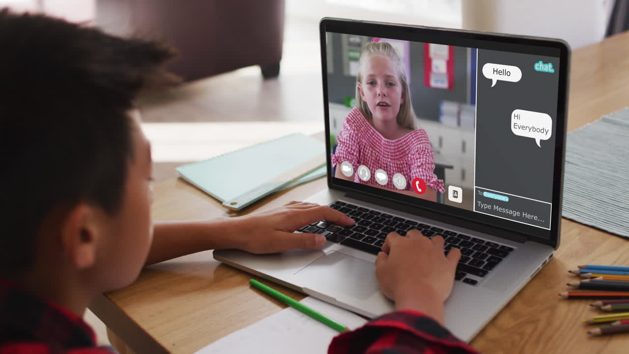 chico asiático haciendo una videollamada con un compañero de clase en una computadora portátil en casa