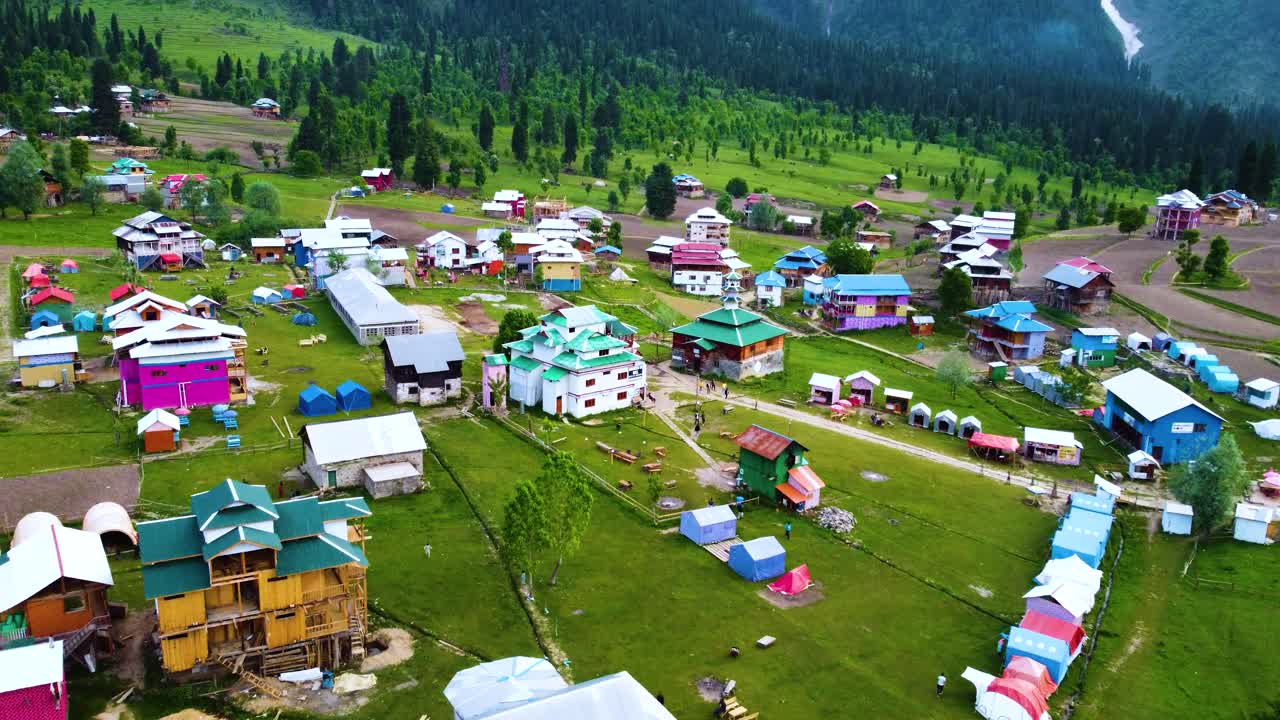 푸른 숲과 아름다운 풍경으로 둘러싸인 카슈미르의 아랑  마을의 공중 사진, 전통적인 목조 건축물을 보여줍니다.