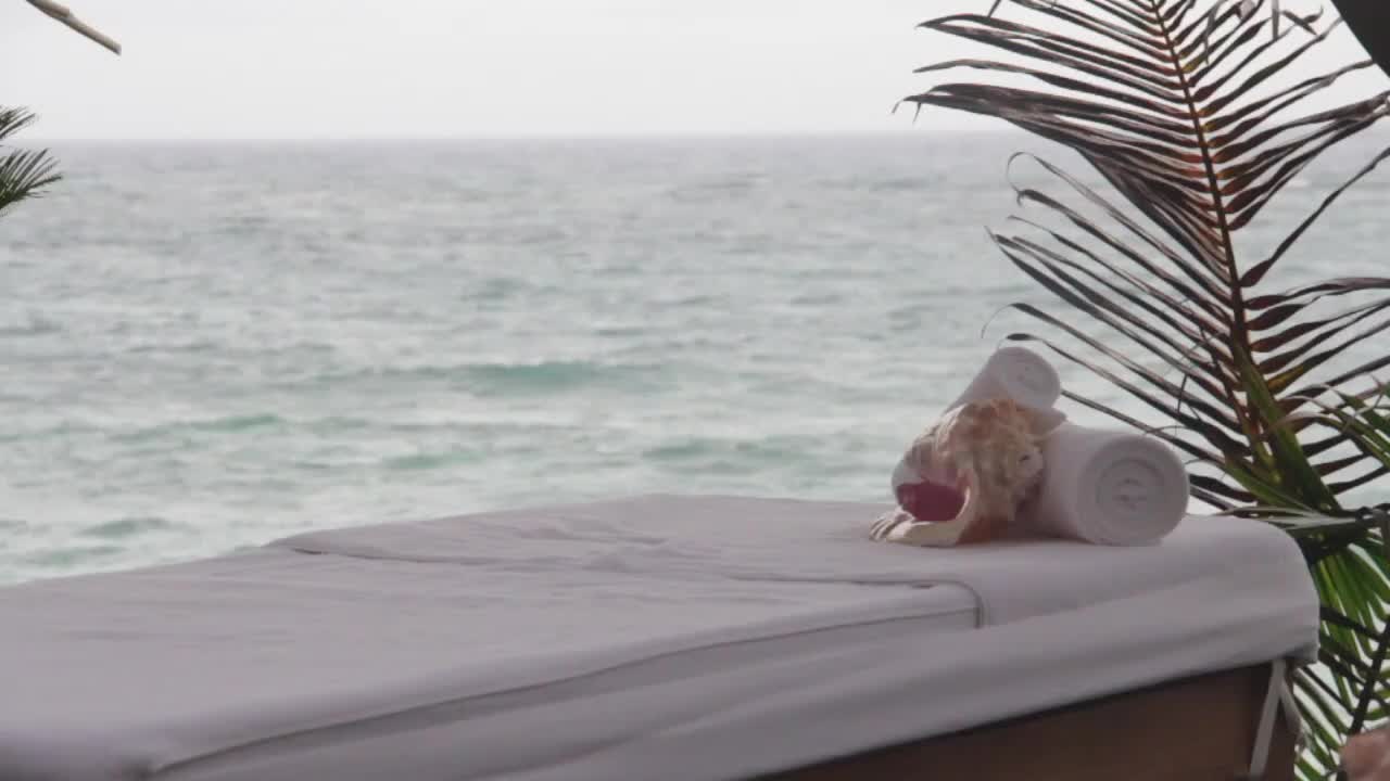 massage table on foreground, and caribbean ocean in the back during a cloudy and quiet day