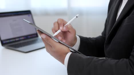 hombre de negocios que usa un lápiz estilográfico firmando un contrato en una tableta digital en el trabajo en la oficina en el interior. escriba a mano el acuerdo de negocios del contrato. firma electrónica en una computadora tableta.