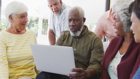 happy senior diverse people talking and using laptop at retirement home
