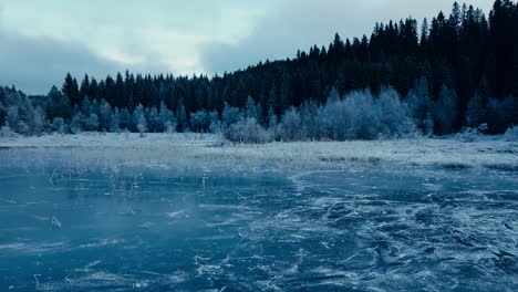 indre fosen, trondelag county, norway - omundvatnet's frozen expanse encircled by coniferous trees - drone flying forward