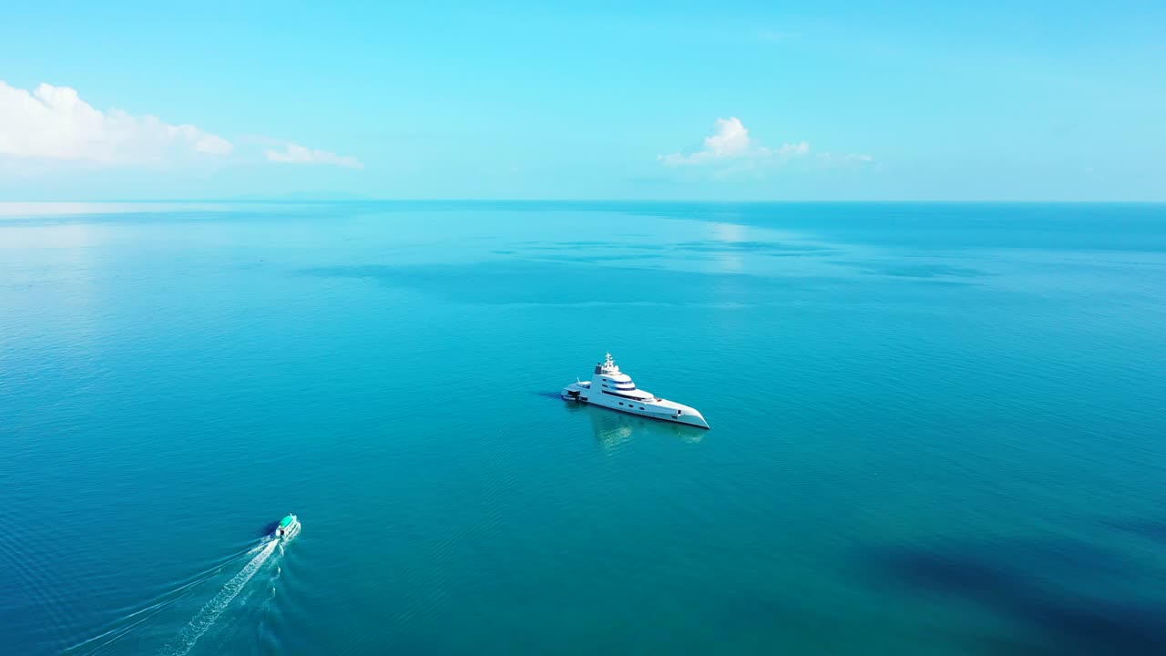 Schöne große Yacht ankert in einer ruhigen blauen türkisfarbenen Lagune und ein Boot segelt nahe der Küste einer tropischen Insel.