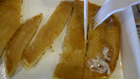 cerca de la mano del niño con cuchillo y tenedor. el niño está cortando panqueque.