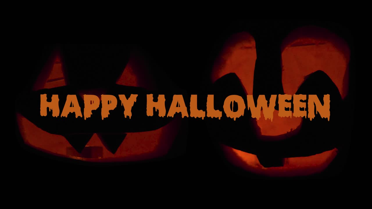 Due Jack O' Lantern brillano al buio con animazione testuale che augura Buon Halloween: decorazioni di zucche intagliate con candele accese all'interno.