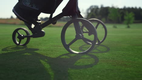 Golf-player-using-clubs-trolley-on-course.-Golfer-legs-walk-take-sport-equipment