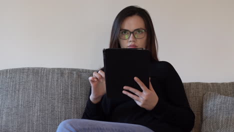 handheld portrait of a serious young woman working from home using a tablet