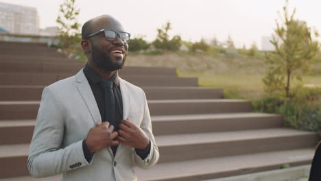 two black businessmen shaking hands and speaking outdoors