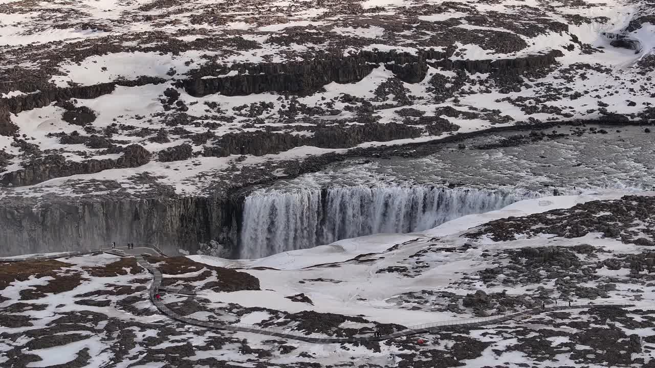 Snowy aerial view of Dettifoss waterfall in Iceland’s rugged northeast, featuring icy cliffs, flowing water, and dramatic highland terrain in winter.