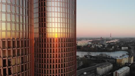 Hermosa-Vista-De-Drones-Del-Cielo-Rosa-Claro-Y-Riga,-Paisaje-Urbano-De-Letonia-En-Una-Puesta-De-Sol-Dorada-Con-Rascacielos-De-Torres-Gemelas-Zunda-En-Primer-Plano-Que-Reflejan-El-Sol