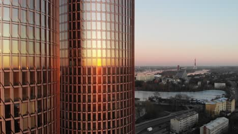 hermosa vista de drones del cielo rosa claro y riga, paisaje urbano de letonia en una puesta de sol dorada con rascacielos de torres gemelas zunda en primer plano que reflejan el sol
