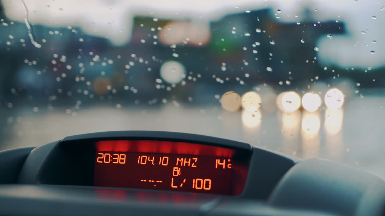 Raindrops fall on the windshield of the car. Inside view. Car dashboard. Close-up