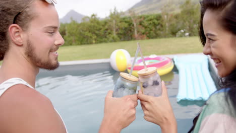 A-young-biracial-couple-enjoys-drinks-by-the-pool