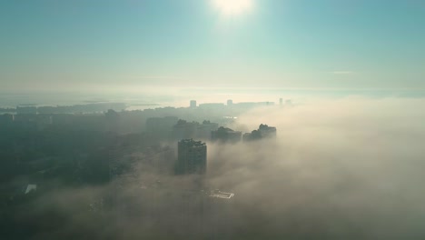 aerial drone footage of flying over the city in fog during dawn