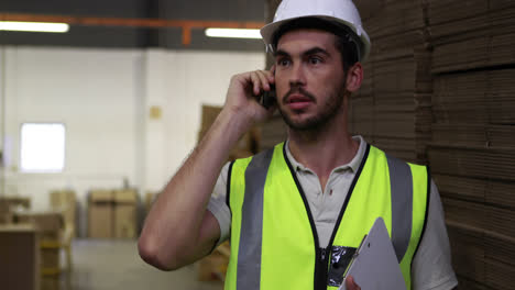 Trabajador-De-Almacén-Hablando-Por-Teléfono-Sosteniendo-El-Portapapeles