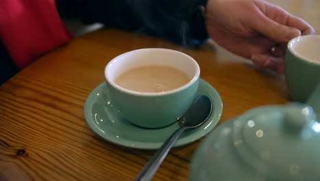 una mujer vertiendo leche en una taza de té