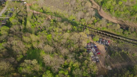 High-establishing-aerial-of-junk-yard-with-rusty-vehicle-cars-surround-by-trees