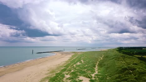 Aerial-flight-over-beautiful-beach-with-breakwater-sea-defence,-UK