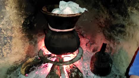 moroccan couscous cooking on a couscoussier steamer to steam it
on a wooden fire in a fireplace, smoke and flame surround the pot