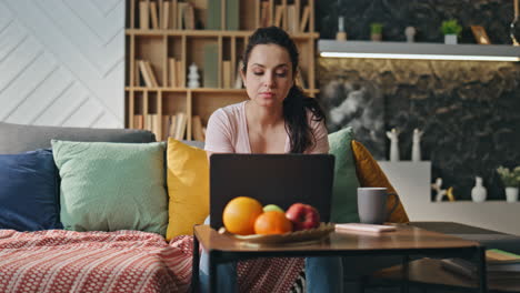 chica desmotivada estudiando en línea sentada en el sofá de casa con café. estudiante cansado