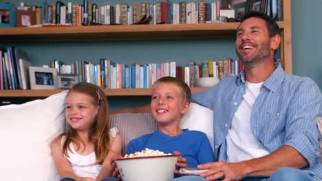 family eating popcorn while watching tv