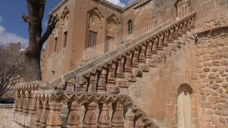 die kamera sieht das prächtige gebäude der mor-behnam-kirche, eine der wichtigsten kirchen von mardin, und die prächtige steintreppe davor, die sie von unten nach oben neigt