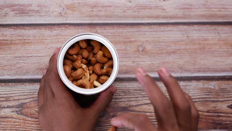 Hand pick cashew nut from a container top view ,