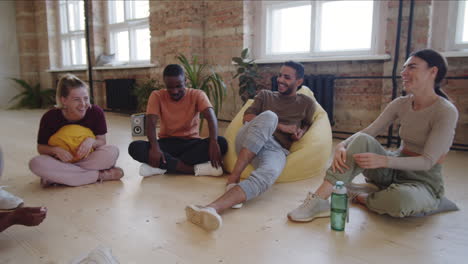 group of young multiethnic dancers chatting after training in studio