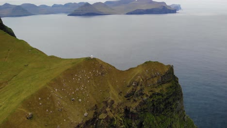 Antena-De-Espectacular-Caída-De-Acantilado-Enorme-En-El-Faro-Kalsoy-En-La-Hermosa-Isla-De-Kallur-En-Las-Islas-Feroe-En-Un-Día-Nublado