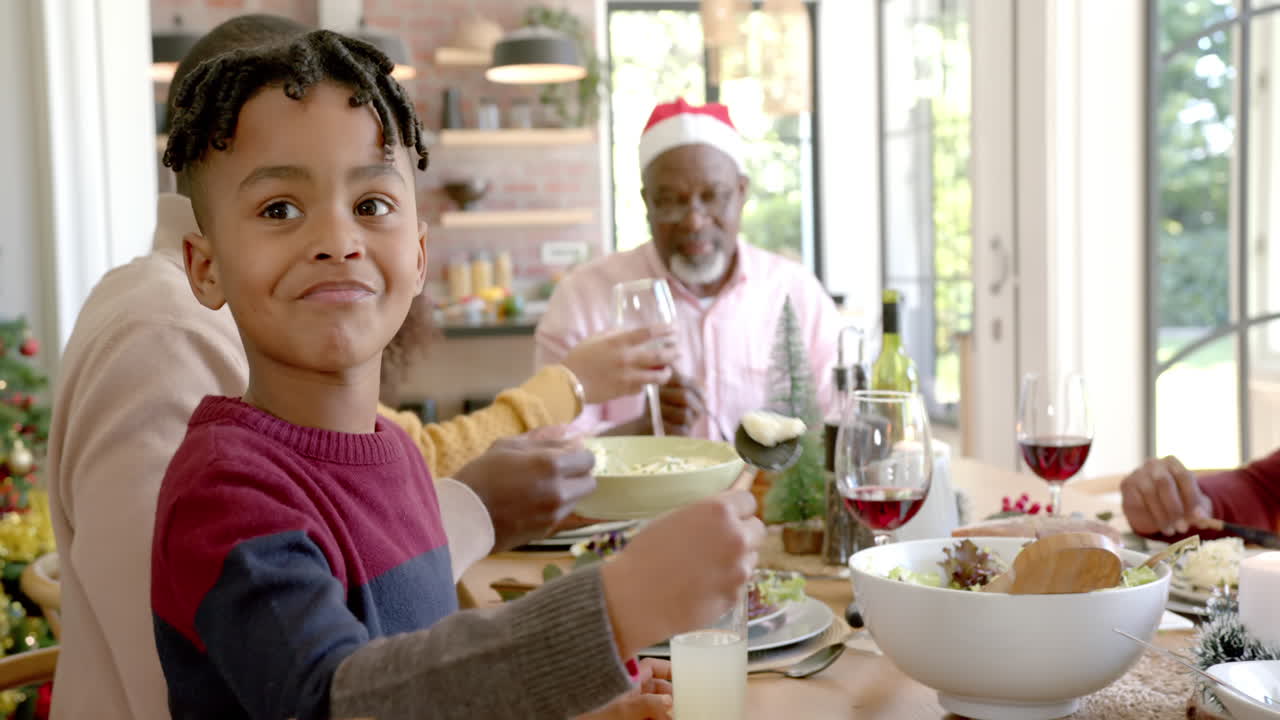 Figlio afroamericano felice che sorride alla famiglia multigenerazionale al tavolo della cena di Natale