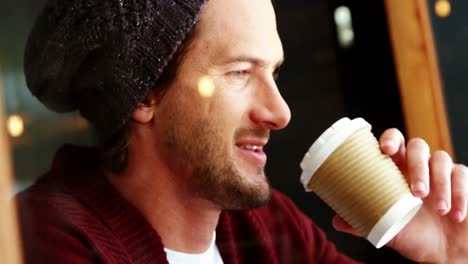 man using mobile phone while having cup of coffee