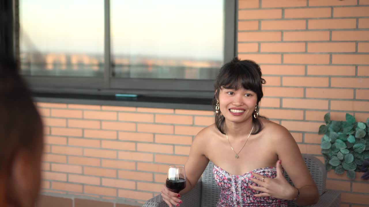 Woman enjoying wine and conversation on a city balcony