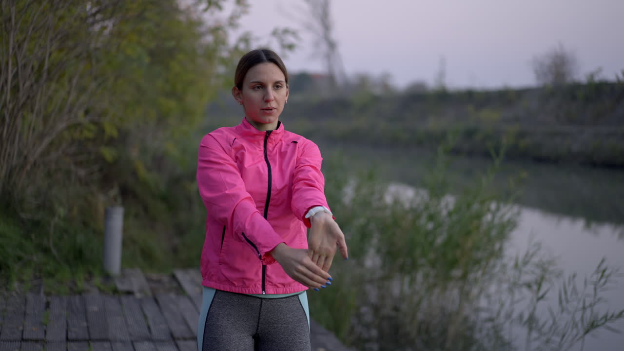 Woman Stretching Outdoors by a River Before a Run
