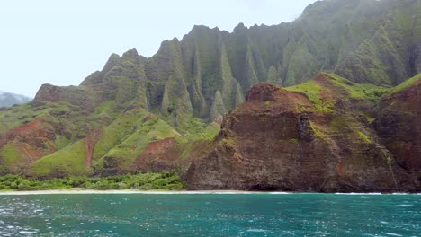 4K-Hawaii-Kauai-Boating-on-ocean-floating-left-to-right-with-left-to-right-pan-of-waves-crashing-against-rocky-cliffs-with-mountains-in-background