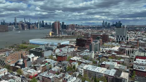 vuelo lento hacia adelante sobre el vecindario americano al lado del río y el horizonte durante un día nublado en el fondo - ciudad de nueva york, estados unidos