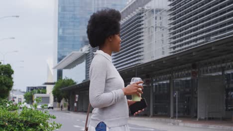 Empresaria-Afroamericana-Caminando-Con-Teléfono-Inteligente-Y-Café-En-La-Ciudad