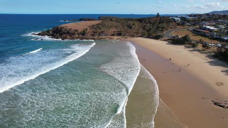 tourists at the golden sand shoreline of emerald beach in new south wales, australia