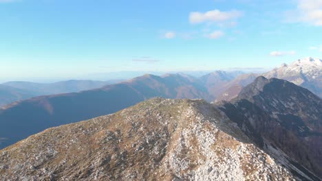 Flying-over-mountain-ridge-revealing-three-people-on-top-of-mountain