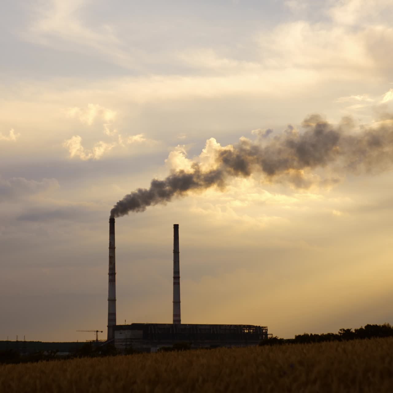 Two plant pipes hovering above the industrial zone. One of the pipes produces heavy smoke