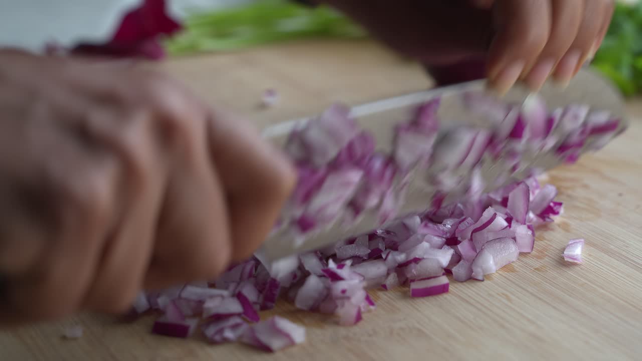 Using a knife to chop up red onions into smaller pieces to cook a meal two cans of beans rice plantain avocado red onion and cilantro
