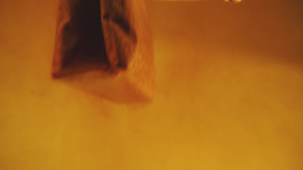 primer plano de la bolsa de té difundida en un vaso transparente. macro cámara lenta del proceso de elaboración de hierbas.