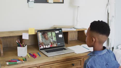 Niño-Afroamericano-Levantando-Las-Manos-Mientras-Realiza-Una-Videollamada-En-Una-Computadora-Portátil-En-Casa