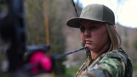 woman wearing camouflage preparing to shot a bow and arrow