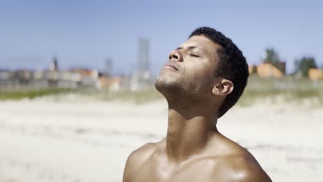 una toma en primer plano de un hombre negro en una playa soleada en galicia, españa, poniéndose y quitándose sus gafas de sol con una sonrisa confiada, capturando el ambiente relajado y elegante de un día de verano en la costa.