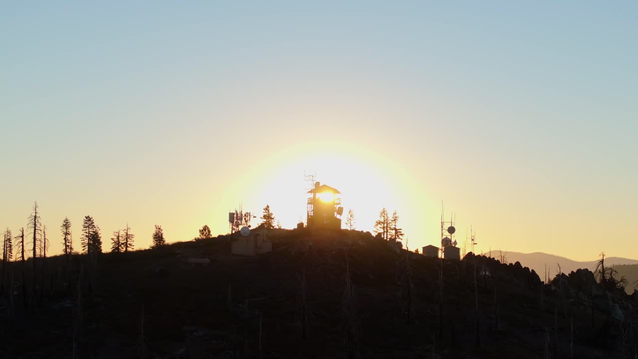 평화로운 환경에서 나무로 둘러싸인 안테나와 함께 산의 전망대 뒤에 해가 뜨고
